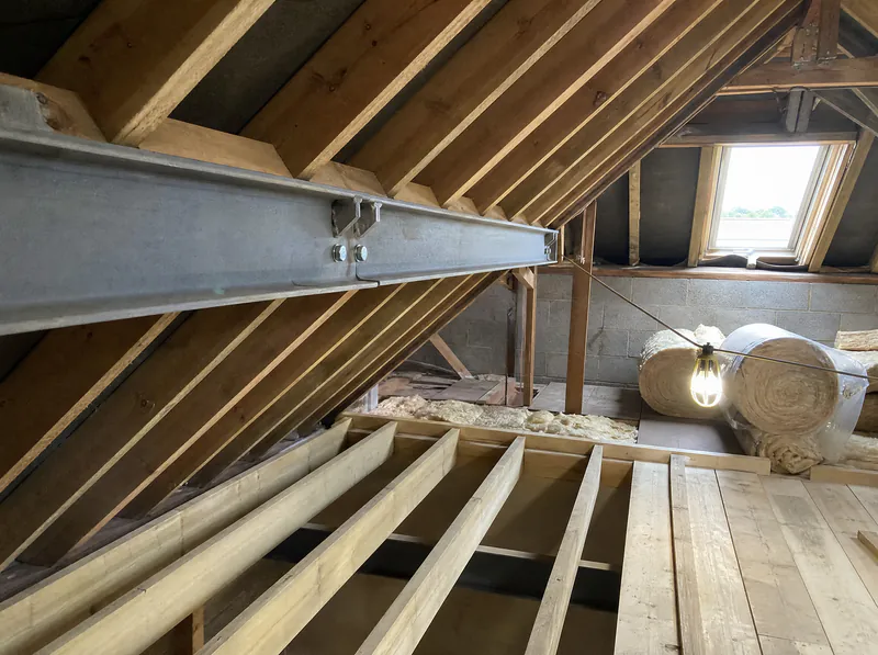 Steel beam at purlin level supporting cut rafters during an attic conversion