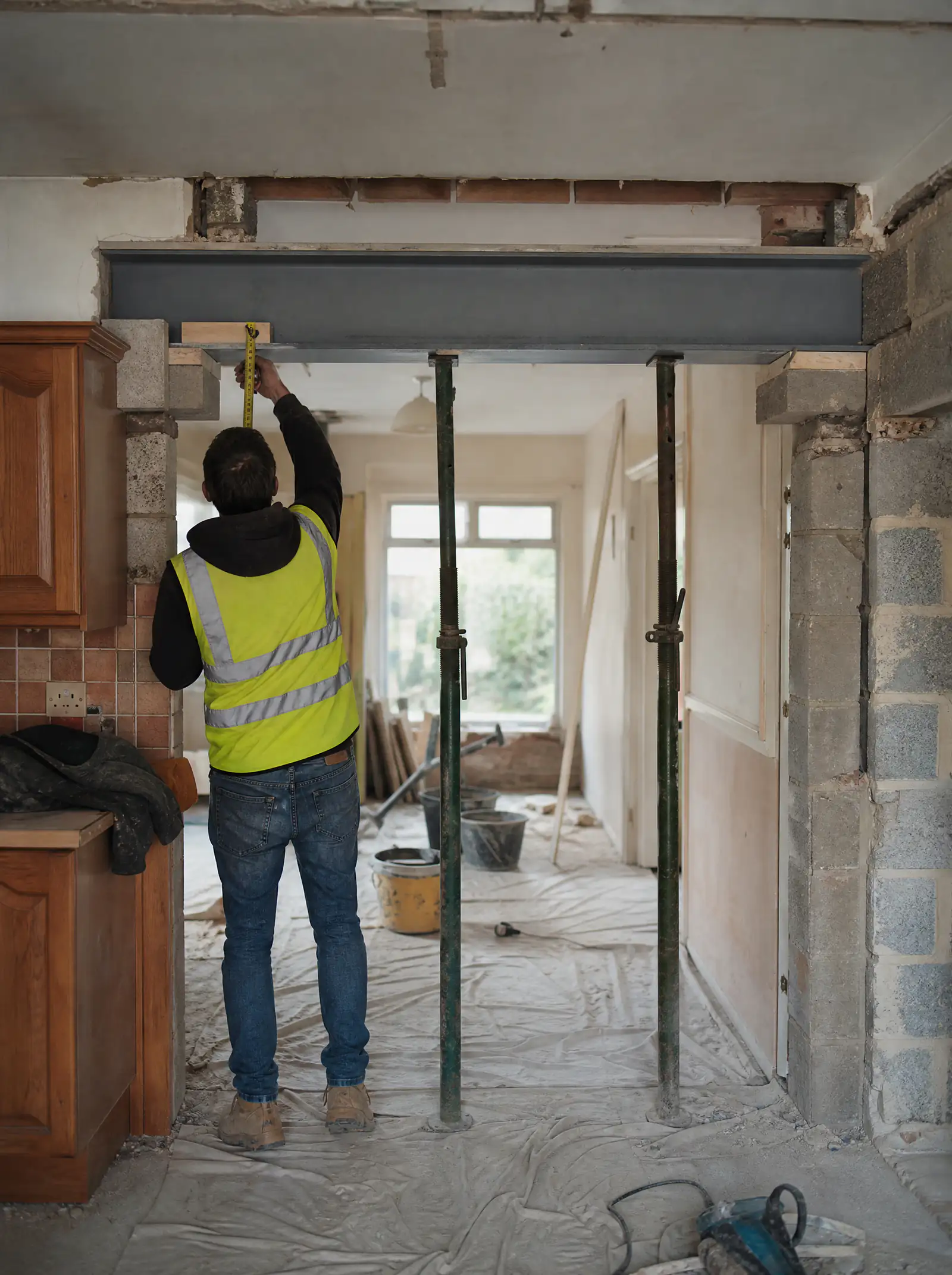 Structural engineer checking a newly installed steel beam and padstone in a Dublin semi-detached house mid-renovation