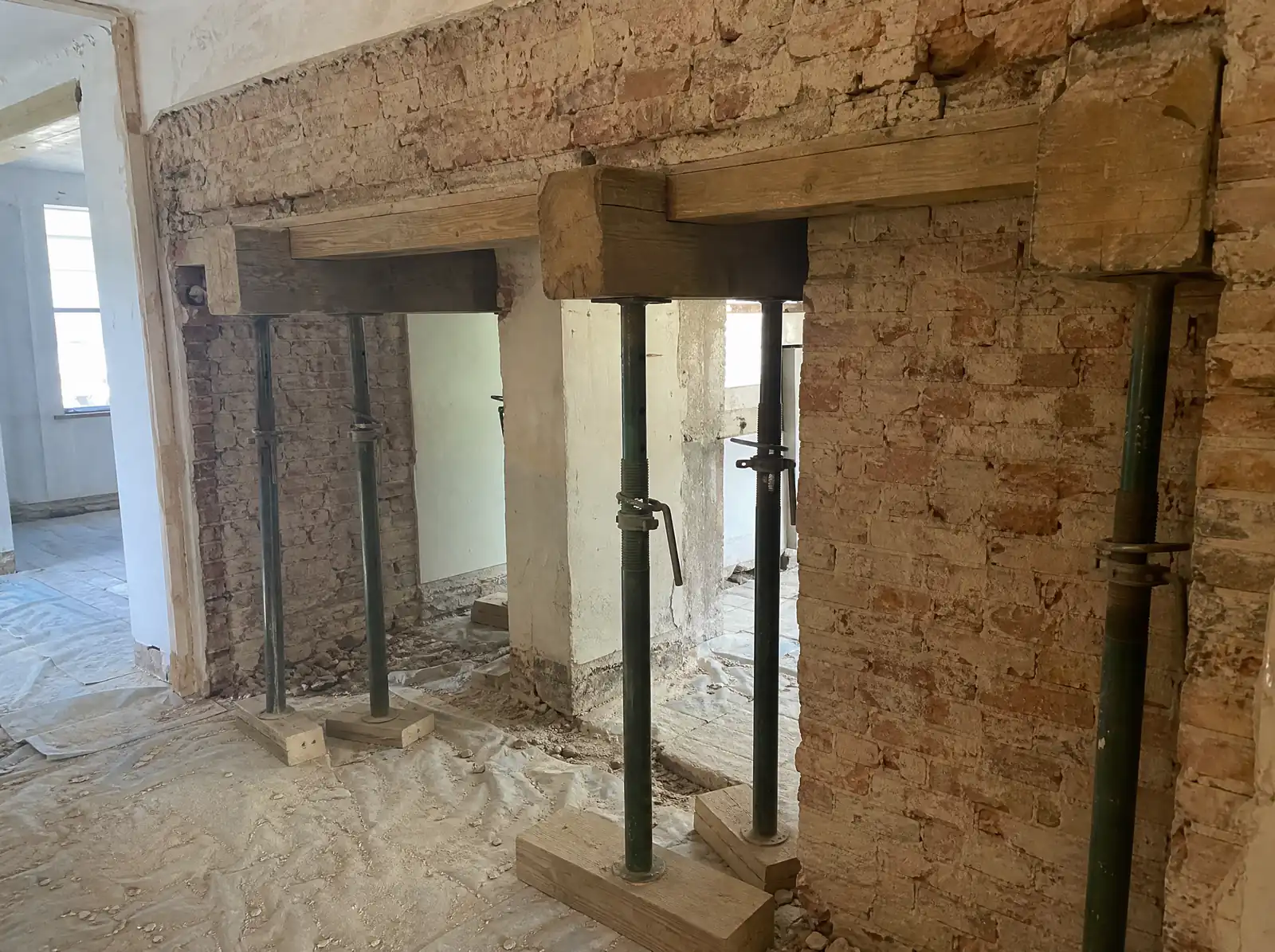 Timber needles and adjustable steel props supporting a brick wall above a new opening