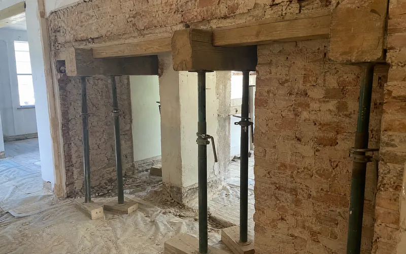 Timber needles and adjustable steel props supporting a brick wall above a new opening